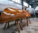 Bateau en bois fraîchement verni avec une laque pour bateaux, posé sur des cales dans le hangar du chantier naval, avec une surface d'un brillant profond